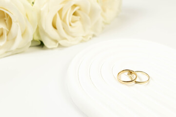 Wedding white roses and gold wedding rings on white background. Wedding composition, white arch...