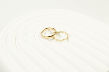 Top view of wedding gold rings on white background. Abstract wedding composition, white arch tray, podium. Copy space, flat lay.