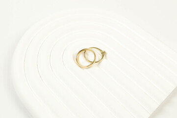 Top view of wedding gold rings on white background. Abstract wedding composition, white arch tray, podium. Copy space, flat lay.