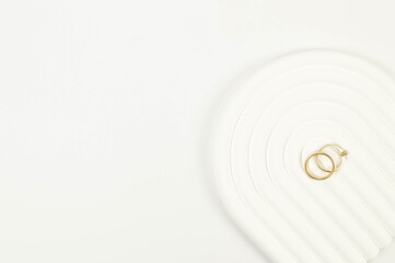Top view of wedding gold rings on white background. Abstract wedding composition, white arch tray,...