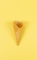 Top view of ice cream waffle cone on yellow background. Summer wallpaper, flat lay, copy space.