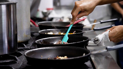 Person cooking and preparing traditional Thai cuisine in pans.