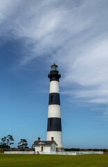 Lighthouse in the Outer Banks of North Carolina against the blue sky surrounded by green grass