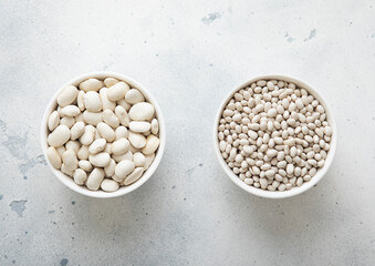 Two bowl plates with large and small raw dry beans on kitchen table.Macro.