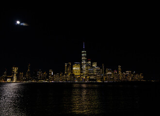 the view of the city at night from the water in the foreground