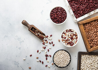 Dry raw white red and mixed beans in ceramic bowls and wooden boxes on light table.Macro.