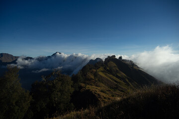 Misty mountains bathed in sunlight with a clear blue sky