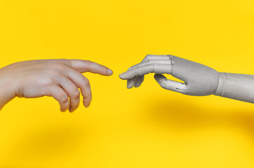 The hand of a robot,a golem,a mechanical man reaches out to the fingers of a real man.A parody of...