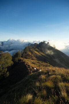 A serene mountainous landscape with clouds rolling over distant peaks at sunset