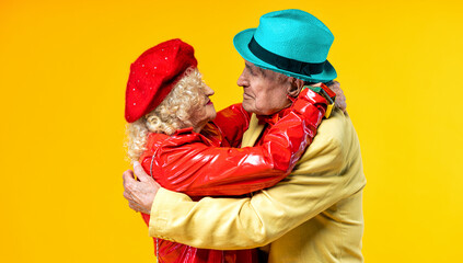 Beautiful senior old couple wearing fancy party clothes acting in studio on a colored background....