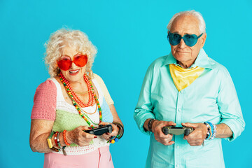 Beautiful senior old couple wearing fancy party clothes acting in studio on a colored background....