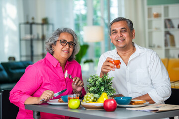 senior Indian asian mid age couple having fun during a breakfast at home.
