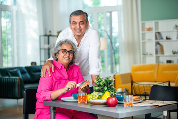 Happy cheerful Indian asian old senior couple posing for photo while having breakfast