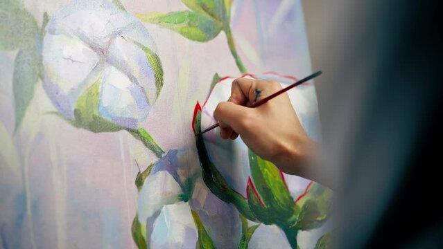 close up in an art studio a painting with flowers the artist sitting the details on the painting with red paint