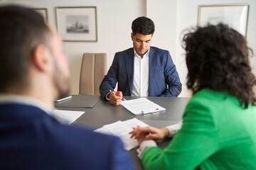 Three people are sitting at a table with papers in front of them