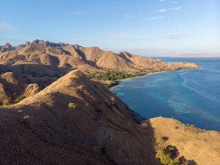 Aerial view of a serene coastal landscape with rolling hills and clear blue waters