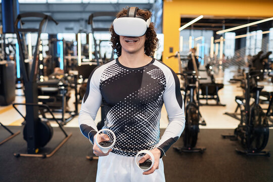 Waist up portrait of smiling man wearing VR headset in gym enjoying immersive experience copy space