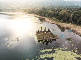 Aerial view of a serene temple complex surrounded by a lake with vegetation.
