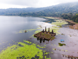 Aerial view of a serene lake with a traditional temple surrounded by lush greenery