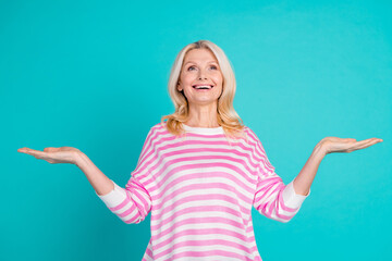 Portrait of nice person with wavy hair wear striped pullover palms comparing objects look empty space isolated on blue color background