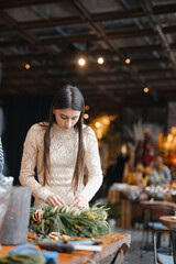 A charming young woman fully engaged in a Christmas decor crafting class.