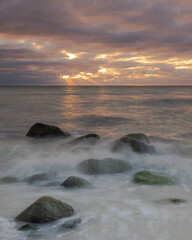 Scenic view of a rocky beach against the sea at sunset