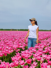 A woman stands elegantly in a field of vibrant pink tulips, surrounded by their beauty and serenity.
