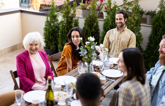 Storytelling image of a multiethnic group of people dining on a rooftop. Family and friends make a reunion at home ad dining outdoor.