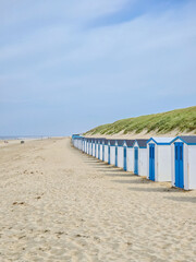 A vibrant row of beach huts line the sandy beach under a clear blue sky, adding a splash of color...