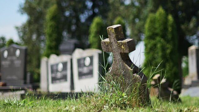 Old concrete christian cross tombstone on a graveyard burial ground