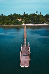 a dock stretches over the water toward the small island of an island