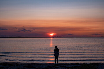 Fototapeta premium a person is standing in the ocean with a kite flying above