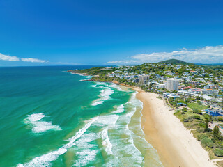 Aerial of the foamy waves of the ocean hitting the sandy shore in Coolum, Sunshine Coast QLD