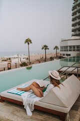 Obraz premium Caucasian woman posing on a lounger at a hotel's swimming pool