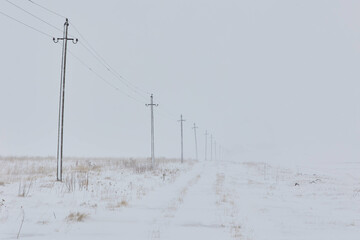 Row of utility poles standing in a snowy field. Georgia, Paravani Lake