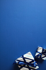 Two elegant striped gift boxes with dark blue ribbons on a blue background. Ideal for use in...