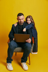 Father working online and his little daughter dressed formal attire pointing to screen against...
