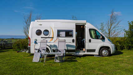 A modern RV is peacefully parked on a lush green field in Texel, Netherlands, surrounded by the...