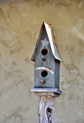 Charming wooden birdhouse perched atop a sturdy pole against a wall