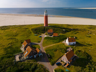 An awe-inspiring aerial view of a majestic lighthouse standing tall amidst the sandy shores of...
