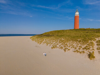 Fototapeta na wymiar A majestic lighthouse stands tall on a sandy beach in Texel, providing guidance and protection to ships navigating the waters.