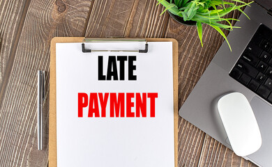 LATE PAYMENT text on clipboard paper with laptop, mouse and pen