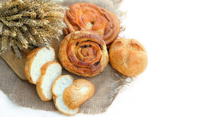 set of Freshly baked breads and wheat ears on burlap close up, white background. top view. Bread...