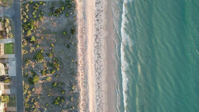 Top-down aerial view of calm waves hitting sand at Aldinga, South Australia, Australia at sunset