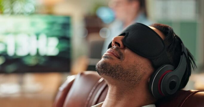 Man, relax and hypnosis with headphones for sound frequency, noise or comfort on living room sofa at home. Calm male person listening to audio or radio waves with ok sign in vibroacoustic therapy