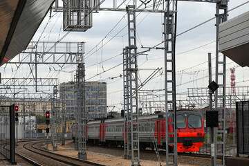 Industrial landscape with arriving passenger train to railroad station on cloudy day