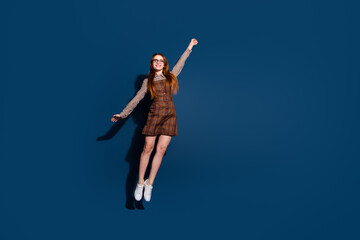 Obraz premium Full length photo of excited cheerful lady dressed plaid outfit jumping high catching arm emtpy space isolated dark blue color background