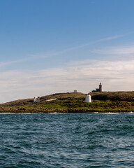 White lighthouse on a small island with a cloudy blue sky in the background