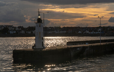 Fototapeta premium Lighthouse illuminated by sunset with a cloudy sky in the background