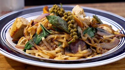 Bowl of Pad Kee Mao Noodles on a wooden table